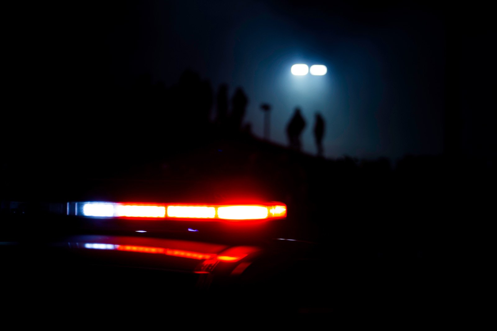 Police-lights-flash-as-people-are-silhouetted-in-the-background-as-a-street-light-glows-from-above